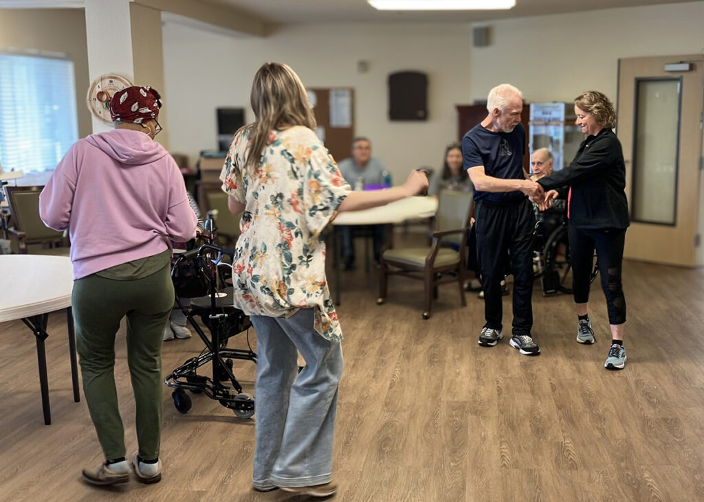 Residents and team members dance together at a community event.