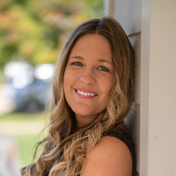 Kari Havens, Resident Services Director at Curtis Creek Senior Living, smiling in a professional outdoor headshot with long wavy hair and a black top.